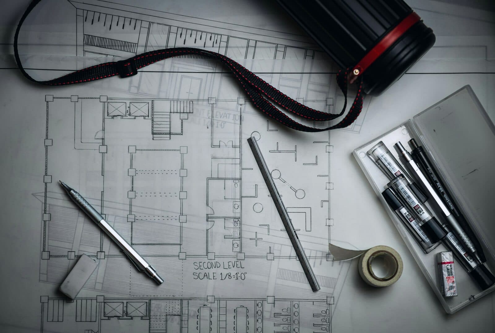 Architectural blueprints laid out with drafting pencils and a metal rule