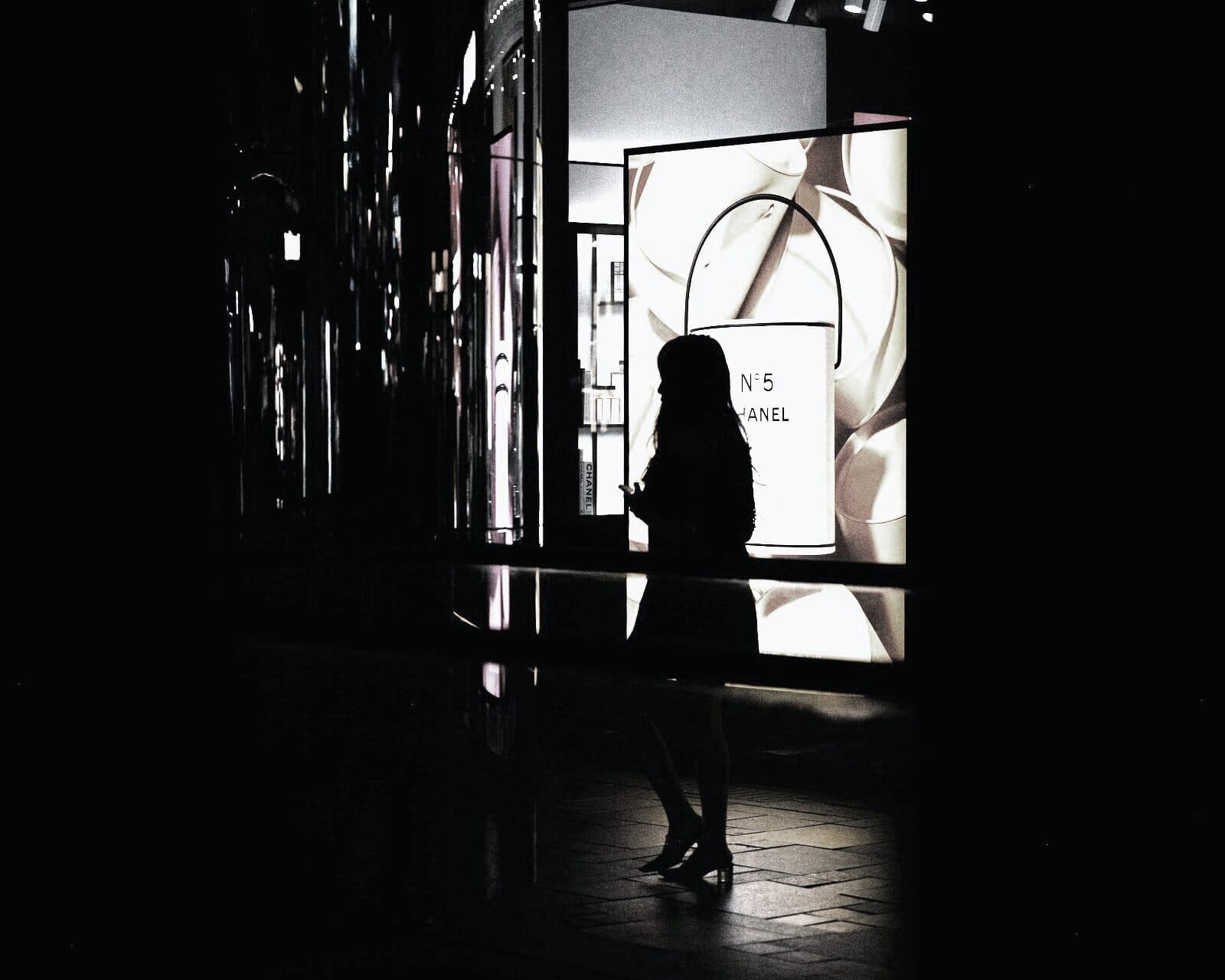 A shopper silhouetted against a lit storefront in a darkened mall